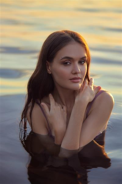 زن جوان زیبا در آب در غروب آفتاب زن مو بلند زیبایی طبیعی در دریاچه