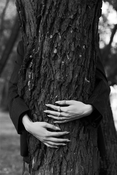 زنی که درختی را در آغوش گرفته و دستانش را روی تنه قرار داده است
