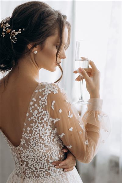 عروس زیبا که لیوان شامپاین در دست دارد