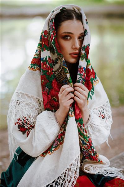 دختری زیبا با لباس سنتی قومی با شنل گلدوزی شده روی سر