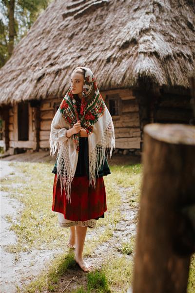 دختر جوان با لباس سنتی اوکراینی در روستا قدم می زند