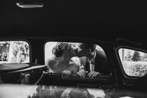 عروس های شاد در ماشین در حال بوسیدن هستند