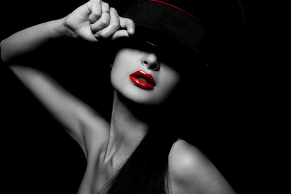 پرتره شیک و جذاب از زن جوان زیبا با لب های قرمز روی پس زمینه مشکی با کلاه