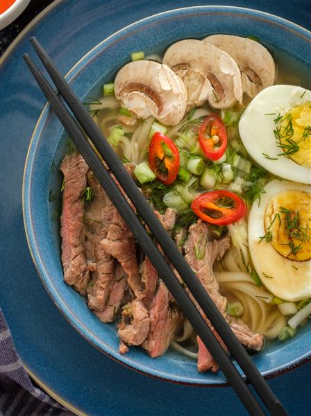 سوپ رامن آسیایی با گوشت گاو تخم مرغ پیازچه و قارچ در کاسه
