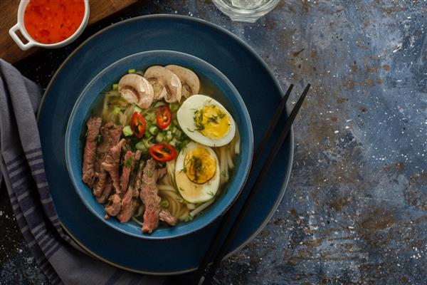 سوپ رامن آسیایی با گوشت گاو تخم مرغ پیازچه قارچ در کاسه تاریک فضای کپی نمای بالا