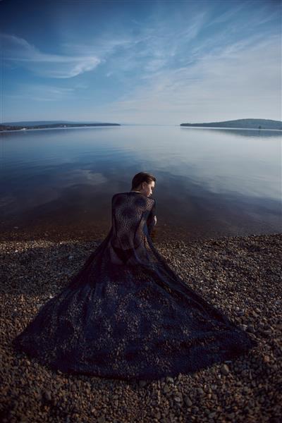 زن زیبای رمانتیک که در نزدیکی دریاچه برکه ای نشسته است زن مرطوب با لباس زیر زیر پرتوهای خورشید در غروب آفتاب موهای بلند زیبایی طبیعی