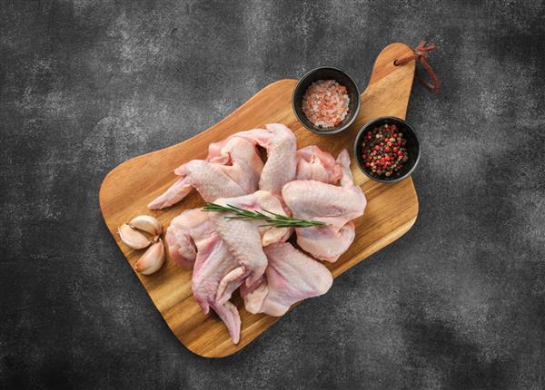 گوشت مرغ خام بال مرغ با ادویه جات نمک و فلفل در زمینه خاکستری
