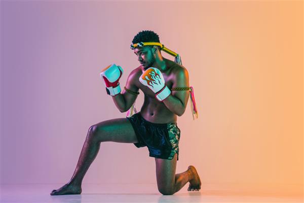 موی تای مرد جوان در حال تمرین بوکس تایلندی روی دیوار گرادیان در نور نئون تمرین جنگنده آموزش هنرهای رزمی در عمل حرکت سبک زندگی سالم ورزش مفهوم فرهنگ آسیایی