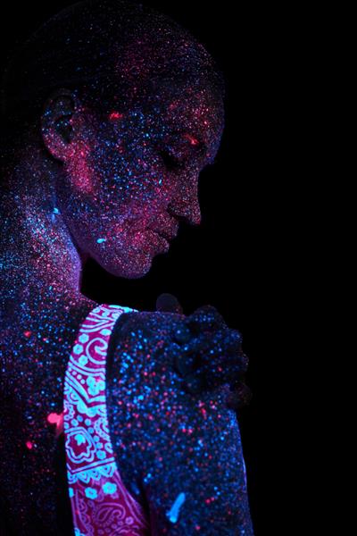 کیهان دختر هنری در نور فرابنفش زن یوگا گرم کردن بدن انجام می دهد تمام بدن با قطرات رنگی پوشیده شده است یوگای اختری سر و صدا خارج از فوکوس