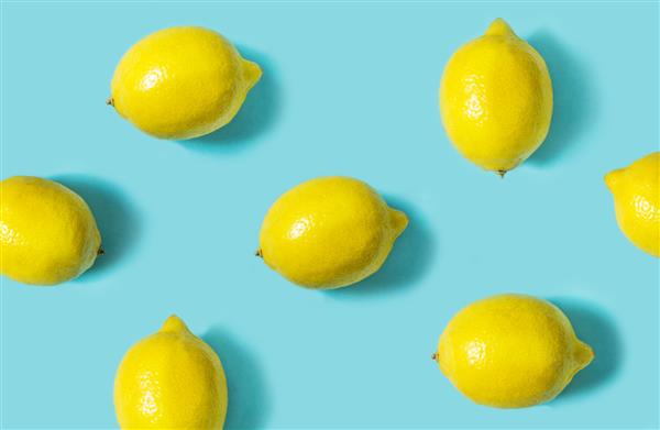 نمای بالای لیموی تازه جدا شده در پس زمینه آبی مفهوم مینیمال میوه