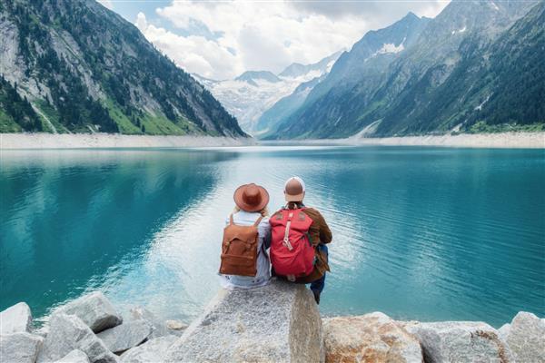 زوج مسافر به دریاچه کوه نگاه می کنند مفهوم سفر و زندگی فعال با تیم ماجراجویی و سفر در منطقه کوهستانی در اتریش