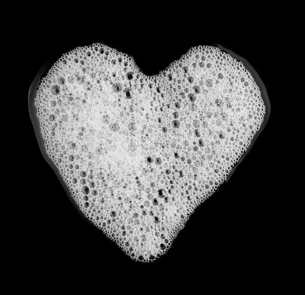 فوم حباب دار شامپو صابون شکل قلب جدا شده بر روی پس زمینه مشکی مفهوم سلامت جسم نمای بالا