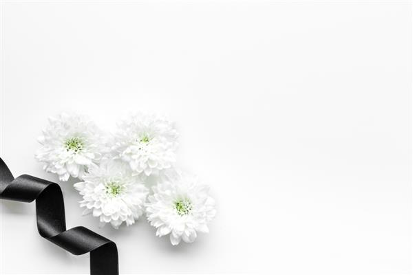 نمادهای تشییع جنازه گل سفید در نزدیکی روبان سیاه روی پس زمینه سفید فضای کپی نمای بالا