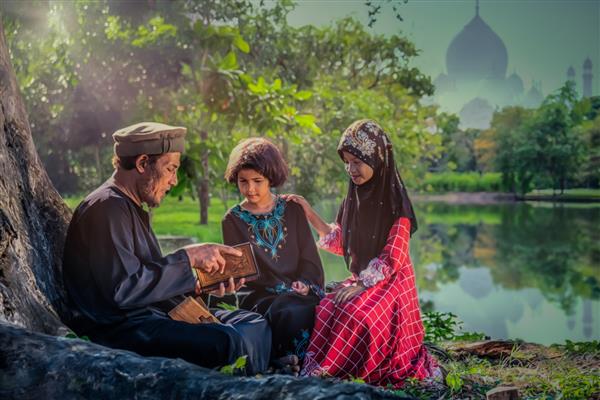 پدر مسلمان به عنوان والدینی که در حال خواندن کتاب مقدس اسلام قرآن برای فرزندانش زیر درختی با پس‌زمینه مسجد آن سوی دریاچه است