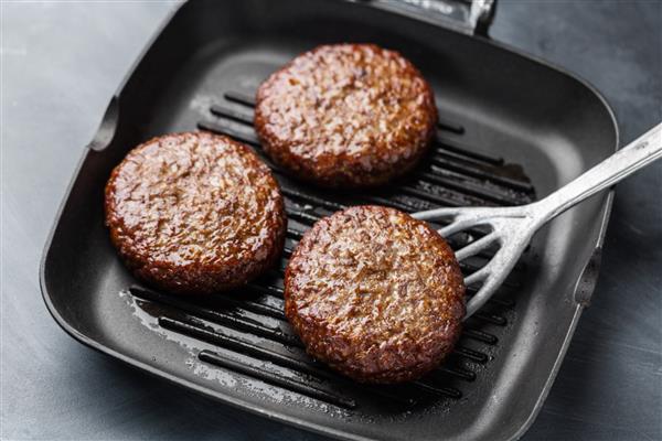 کتلت گوشت تازه روی تابه گریل پس زمینه خاکستری پختن برگر در خانه مفهوم غذای خوشمزه و سالم
