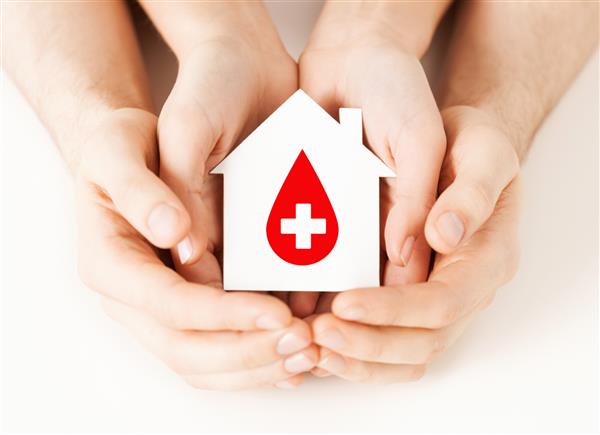مفهوم مراقبت‌های بهداشتی دارو و اهدای خون - دست‌های زن و مرد که دست در دست دارند خانه کاغذی سفید را با علامت اهداکننده قرمز در دست دارند