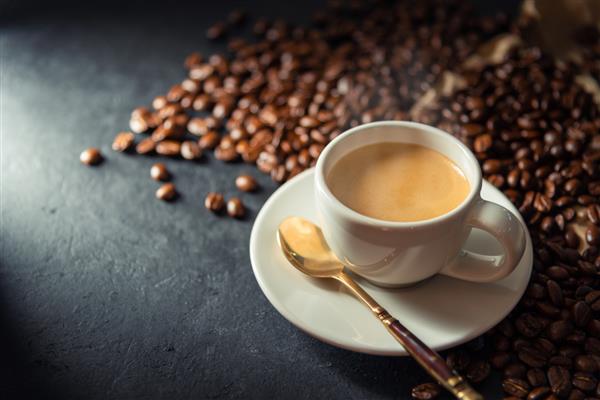 قهوه اسپرسو با دانه های قهوه در پس زمینه صبح