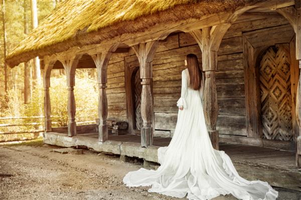 لباس عروس عروس نمای عقب در فضای باز لباس عروس سفید قدیمی روی تراس چوبی قدیمی پرتره زن رمانتیک