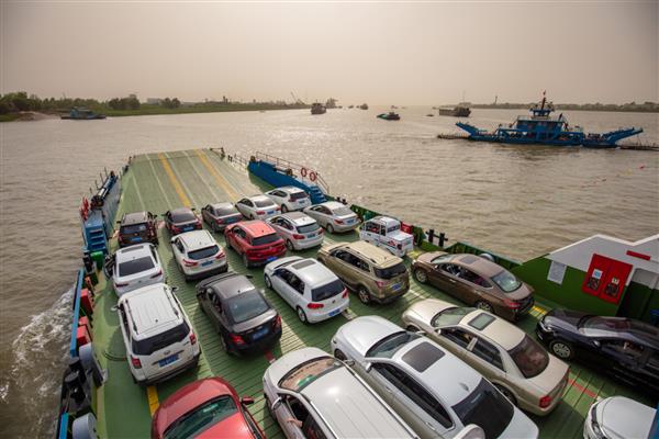 جیوجیانگ چین - 17 آوریل 2021 مسافران در یک سفر جاده ای با کشتی مسافربری ماشین بین جزیره جیانگژو و مرکز شهر جیوجیانگ از رودخانه یانگ تسه عبور می کنند جزیره جیانگژو یک جزیره آبرفتی است