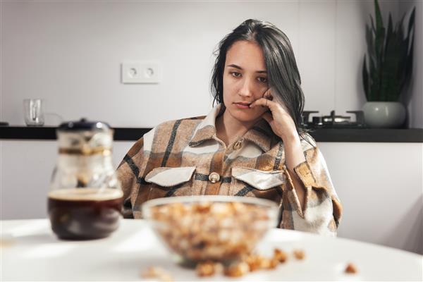 زن جوان خسته به غذا نگاه می کند و نمی خواهد صبحانه بخورد