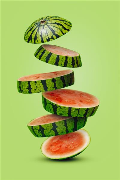 میوه آرایی تابستانی با تکه‌های هندوانه در حال افتادن روی یک پس‌زمینه سبز روشن مفهوم غذای خلاقانه ترکیب انتزاعی