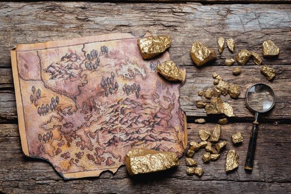 نقشه گنج دزدان دریایی باستانی و سنگ معدن طلایی روی پس زمینه میز تخت چوبی