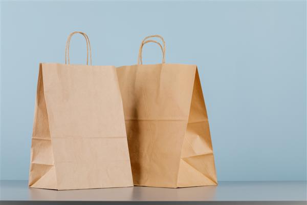 کیسه کاغذی قهوه ای دسته دار کیسه خرید خالی با قسمتی برای لوگو یا طرح شما مفهوم تحویل غذا