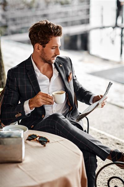 مرد خوش تیپ در حال نوشیدن قهوه و خواندن روزنامه در کافه