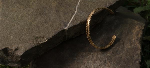 دستبند طلایی بافته شده روی سنگ طبیعی