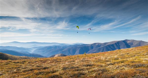 پاراگلایدر در کوه های کارپات در اوکراین پاراگلایدرها در روزهای آفتابی تابستان بر فراز یک دره کوهستانی پرواز می کنند