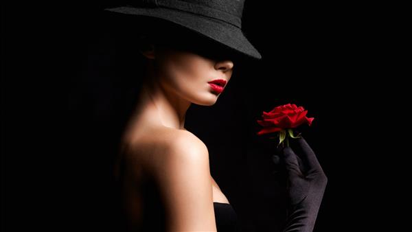 زن جوان زیبا با کلاه و دستکش که گل در دست دارد دختر دوست داشتنی با آرایش و رز قرمز پرتره زیبایی