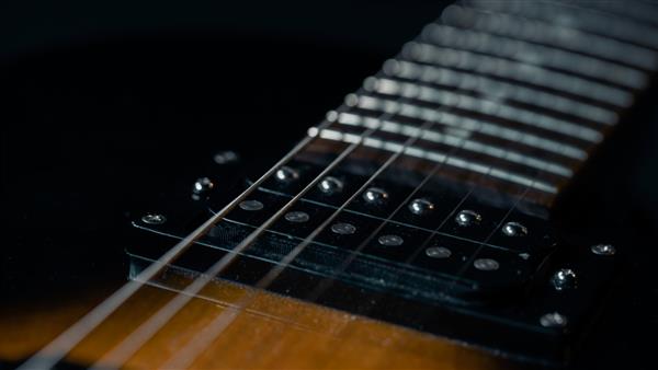 عکس ماکرو با جزئیات از سیم‌های گیتار الکتریک چوبی سبک با جزئیات مشکی