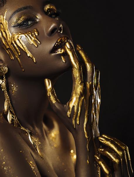 پرتره هنر زیبایی زیبای فوق العاده طلایی آرایش حرفه ای زن آفریقایی پوست لب دست با رنگ قطره طلای مایع مدل مد الهه صورت سکسی چشم های سایه براق درخشش زرق و برق