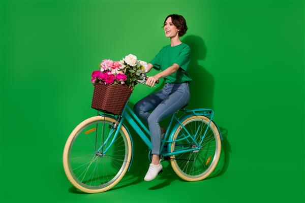 عکس نمایه تمام بدن بانوی شاد دوچرخه سواری خیره کننده فضای خالی جدا شده در پس زمینه سبز رنگ