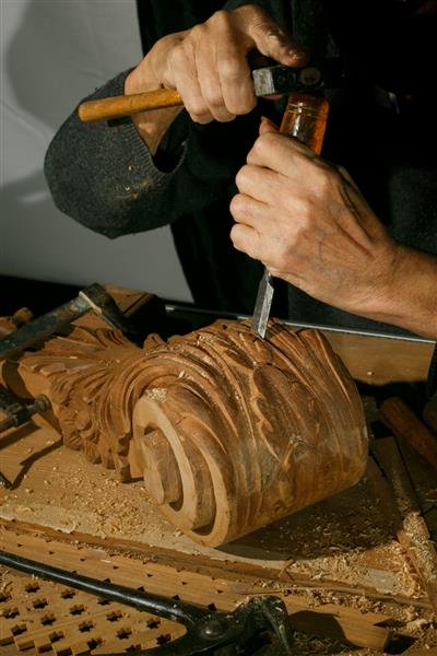 دستان صنعتگر که روی منبت کاری روی چوب کار می کنند با گج و اسکنه کابینت ساز نجاری سنتی