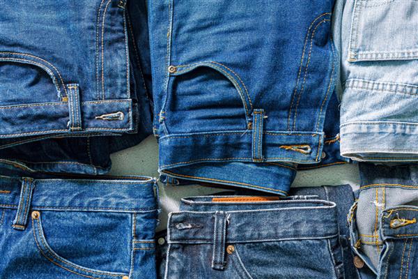 نمای بالای شلوار جین تا شده شلوار جین آبی روی یک دسته از شلوار جین نمای بالا از پارچه های جین مختلف در زمینه سفید چند شلوار جین بلند