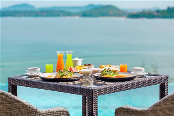 صبحانه تازه در مکانی زیبا با منظره دریا تعطیلات در هتل استوایی لوکس در جزیره رستوران مدرن کنار دریا در فضای باز صبحانه برای دو نفر روی میز با منظره اقیانوس سرو می شود