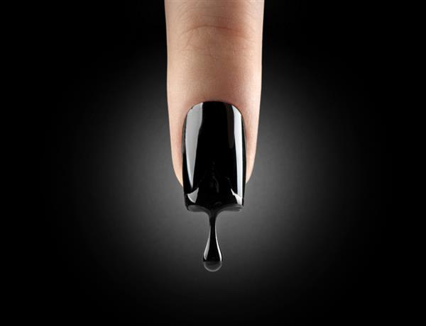 هنر آرایش ناخن لاک ژل مشکی که از ناخن بلند زیبا روی پس زمینه سیاه می چکد انگشت زن با مانیکور تیره و قطره لاک ناخن طراحی هنر مد