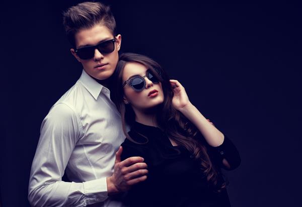 زوج جوان عاشق استودیو در پس زمینه تیره عکس گرفته است