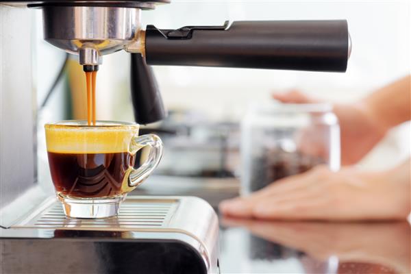 دستگاه قهوه ساز اسپرسو در آشپزخانه جت های قهوه نیروبخش داغ که در فنجان می ریزند