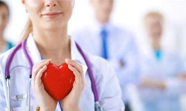پزشک زن با گوشی پزشکی که قلب را نگه داشته است