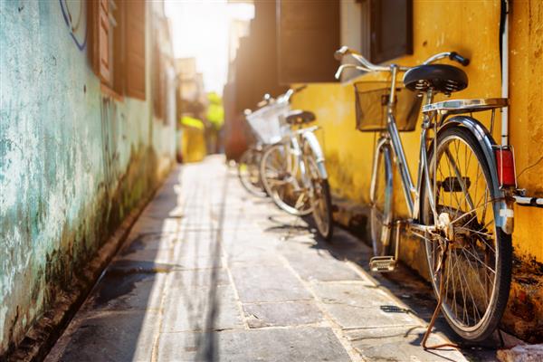 دوچرخه هایی که در تابستان در نزدیکی دیوار زرد خانه قدیمی در خیابان آفتابی پارک شده اند شهر باستانی هوی هویان ویتنام شهر باستانی هوی یک مقصد گردشگری محبوب در آسیا است