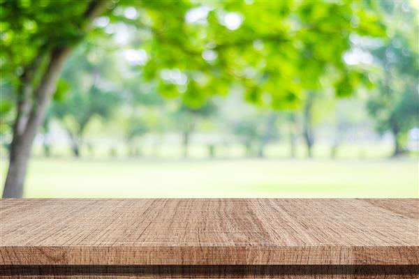 پس زمینه طبیعت میز چوبی برای نمایش غذا و محصولات روی باغ درخت سبز تار طبیعت پارک Blur در فضای باز و میز چوبی با پس زمینه روشن بوکه در بهار و تابستان