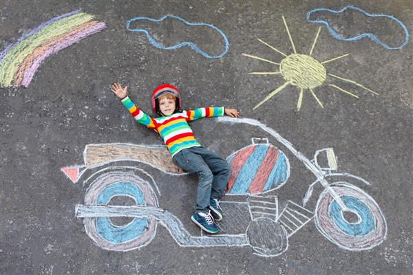 پسر بچه کوچولوی شاد با کلاه ایمنی که با نقاشی موتور سیکلت با گچ های رنگارنگ سرگرم می شود کودکان سبک زندگی مفهوم سرگرم کننده کودکی که رویای آینده و حرفه دارد