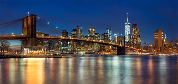 نیویورک - نمای پانوراما از خط افق منهتن با آسمان خراش ها و پل معروف بروکلین در شب اندازه بزرگ