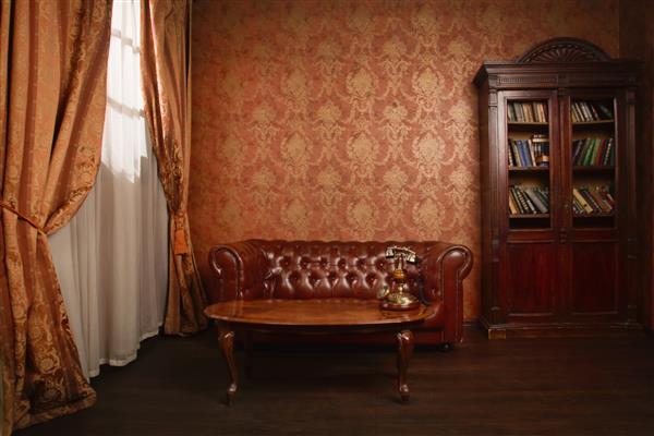 اتاق کتابخانه کلاسیک با صندلی راحتی چرمی میز چوبی و قفسه کتاب
