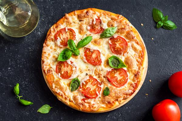 پیتزا مارگریتا در زمینه سنگ سیاه پیتزا مارگاریتا خانگی با گوجه فرنگی ریحان و پنیر موزارلا