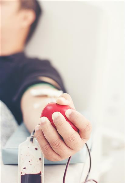 اهداکننده خون هنگام اهدا با یک توپ فنری در دست همچنین تصویر مفهومی برای روز جهانی اهدای خون - 14 ژوئن
