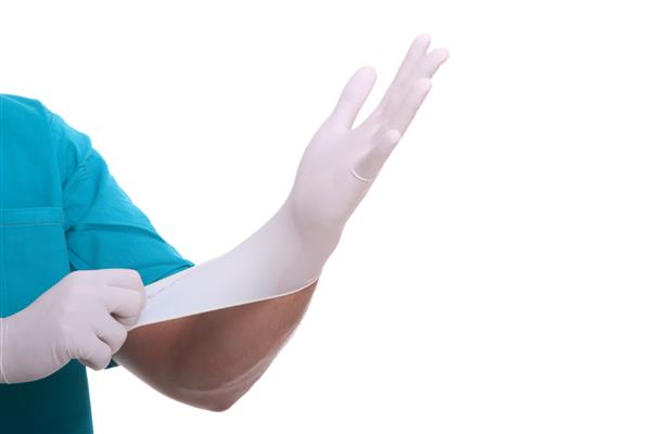 دکتر در حال پوشیدن دستکش پزشکی استریل شده برای انجام عمل
