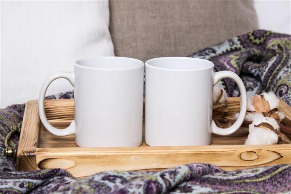 دو لیوان سفید یک جفت فنجان روی یک سینی چوبی Mockup خانه دنج تزئینات پنبه ای و پشمی هدایای زمستانی